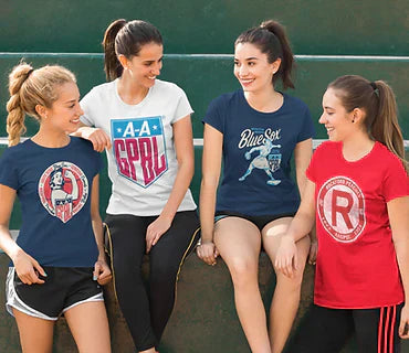 Group of women wearing baseball mom shirts with vintage-style designs, sitting on outdoor steps and chatting.